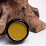 A luxurious jar of Felis Ethnobody Butter lip balm elegantly placed on a polished wooden block.