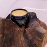 A luxurious jar of Felis Ethnobody Butter lip balm elegantly placed on a polished wooden block.