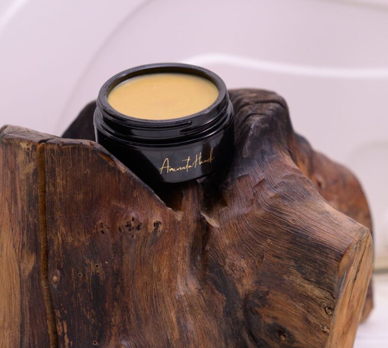 A luxurious jar of Felis Ethnobody Butter lip balm elegantly placed on a polished wooden block.