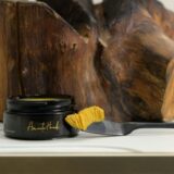 A jar of luxurious yellow Felis Ethnobody Butter beside an elegant spoon, showcasing its rich, creamy texture.