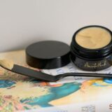 A jar of Gold Coast Overnight Balm and a spoon elegantly placed on an open book, suggesting a moment of self-care.