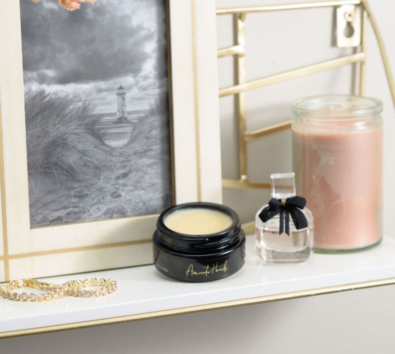 ORI Bakuchiol Restorative Overnight Balm A gold shelf displays a framed picture, elegant candles, and ORI Bakuchiol Restorative Overnight Balm in a chic jar.