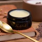 A luxurious jar of le fruit de Albius accompanied by a polished spoon, set on a warm wooden table, exuding natural elegance.