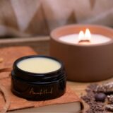 A luxurious candle, a jar of lip balm, showing Body Butter vs. Body Balm elegantly arranged on a wooden surface.