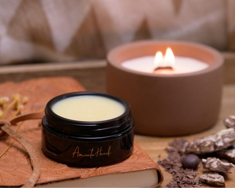 A luxurious candle, a jar of lip balm, showing Body Butter vs. Body Balm elegantly arranged on a wooden surface.