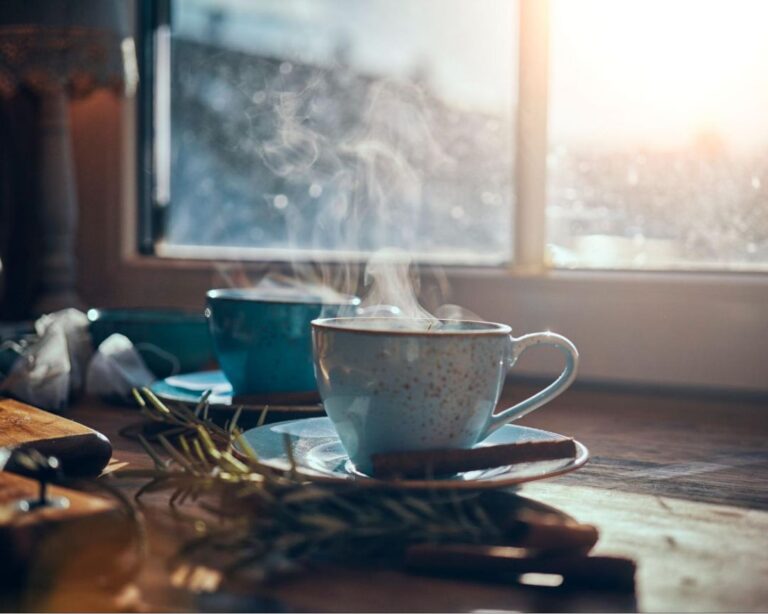 Coffee and tea elegantly arranged on a table beside a sunlit window, creating a warm and inviting atmosphere.