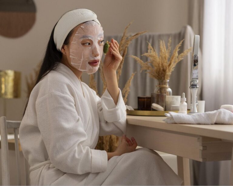 A woman in a luxurious robe sits at a table, enjoying a rejuvenating sheet mask for holistic wellness and skincare.