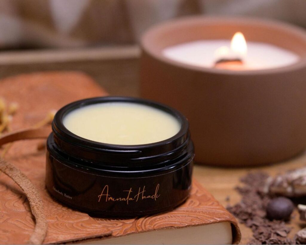 A luxurious jar of lip balm beside a softly glowing candle, highlighting the debate of Shea Butter vs. Cocoa Butter.