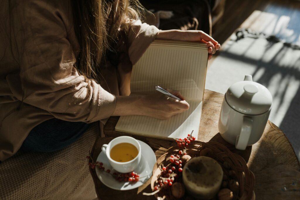 Woman writing journaling prompts for intellectual wellness and self improvement.