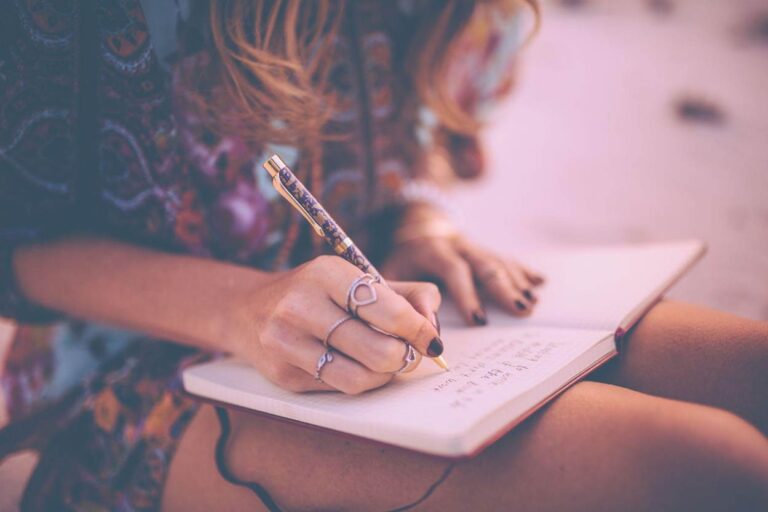 Woman writing journaling prompts for intellectual wellness.