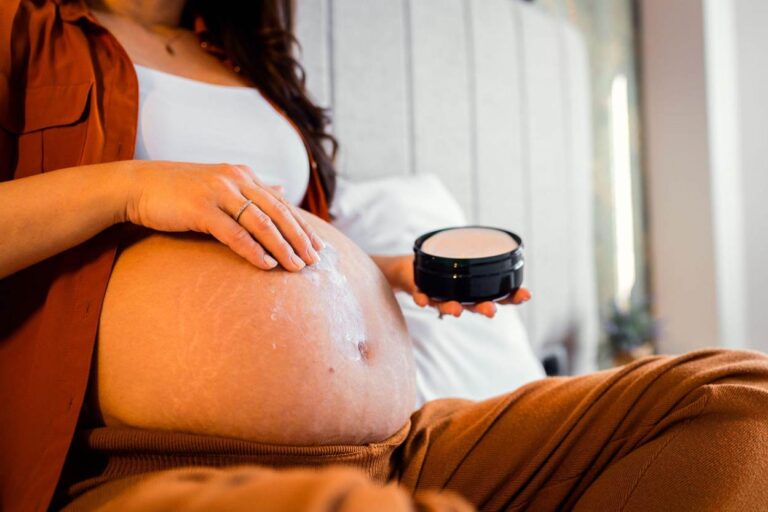 Woman applying raw shea butter lotion body butter to stretch marks.