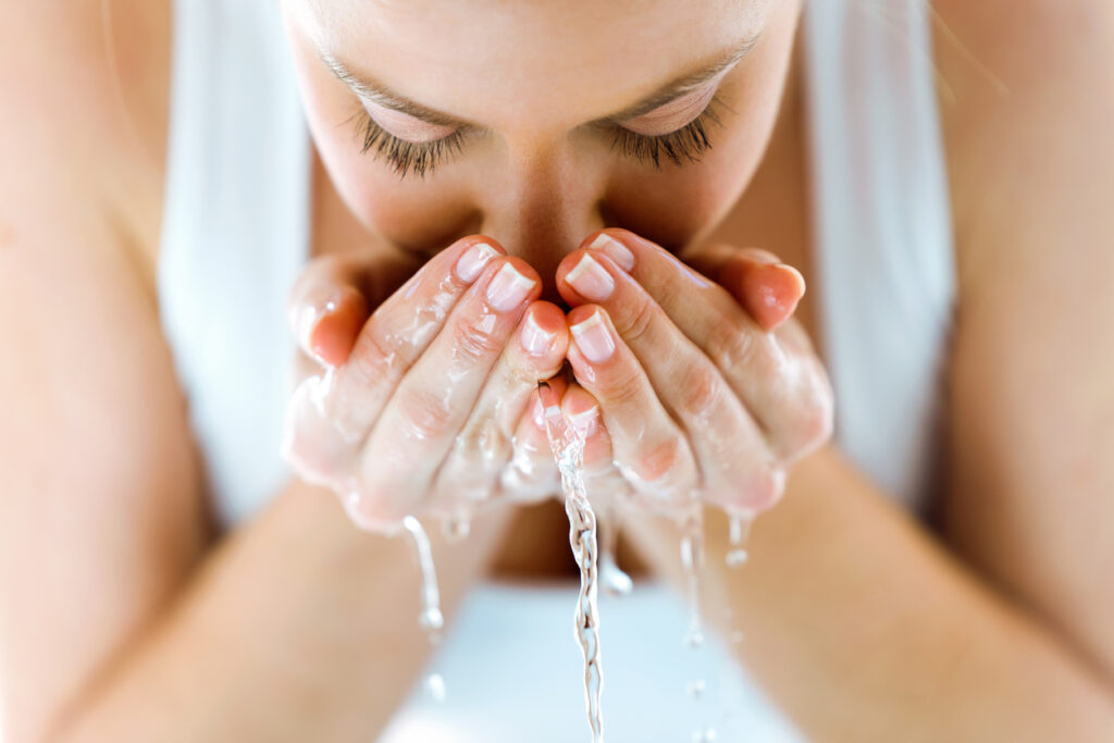 Woman washing face for daily skincare routine.