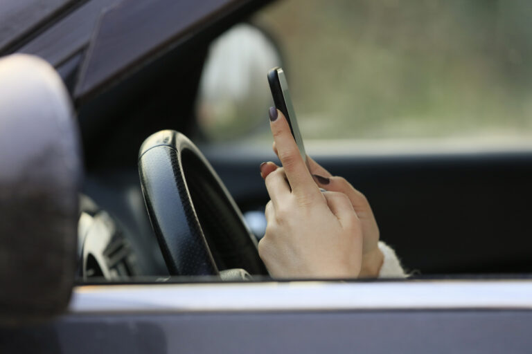 Woman driving car distracted by her mobile phone